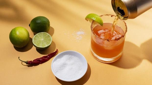 A michelada being poured, with limes and chillies