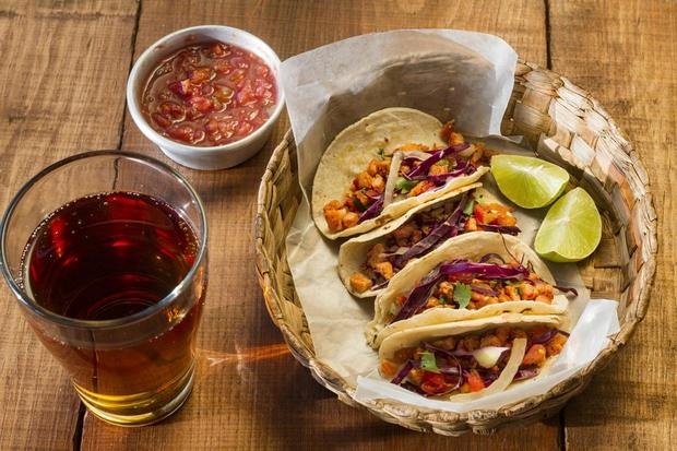 A basket of tacos with salsa on a wooden table